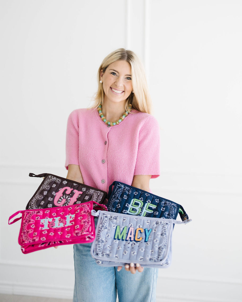 Madison smiling with four monogrammed bandana bags in brown, navy, pink and light blue