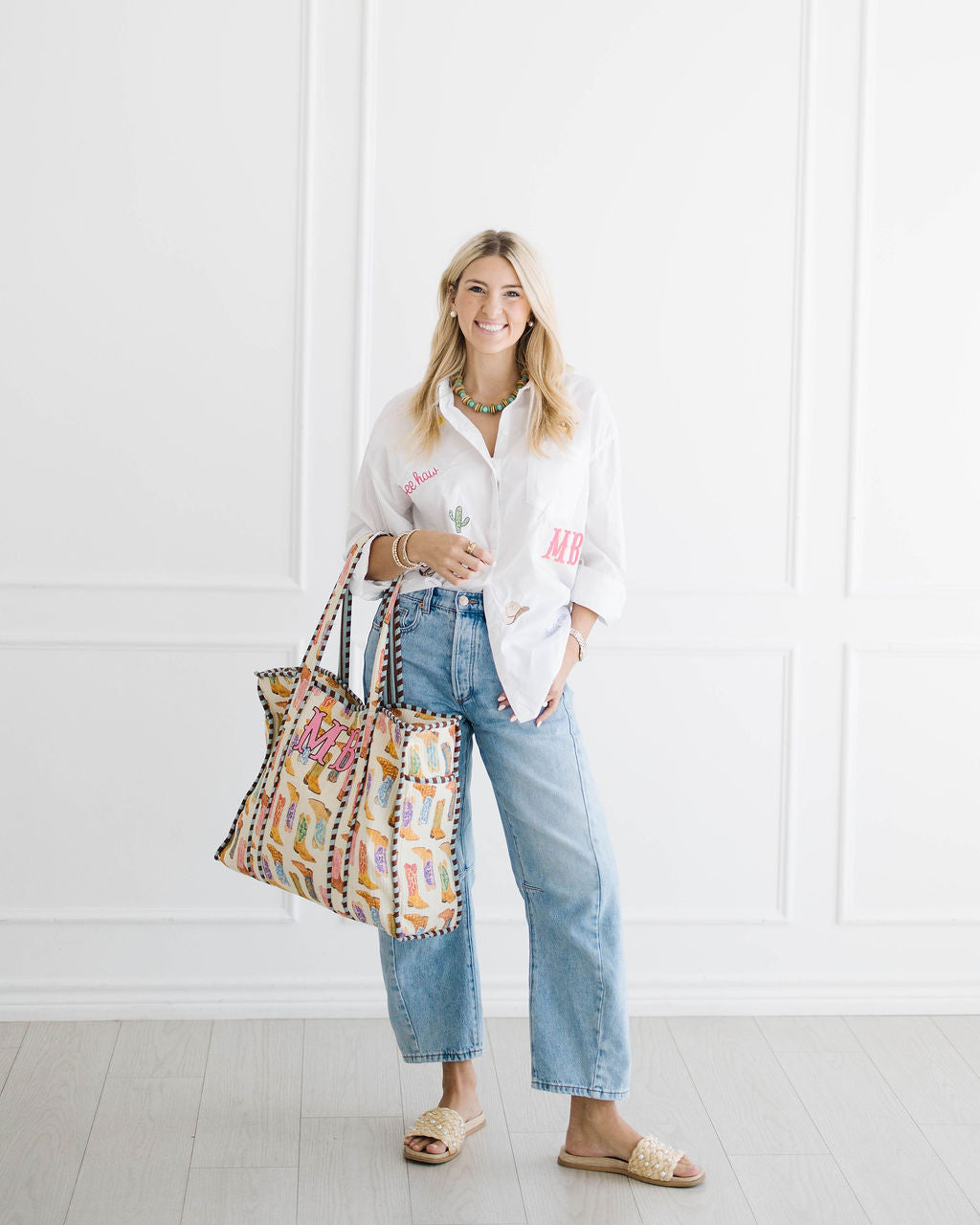Madison in an embroidered All The Things shirt, holding a cowboy boot print tote monogrammed MB
