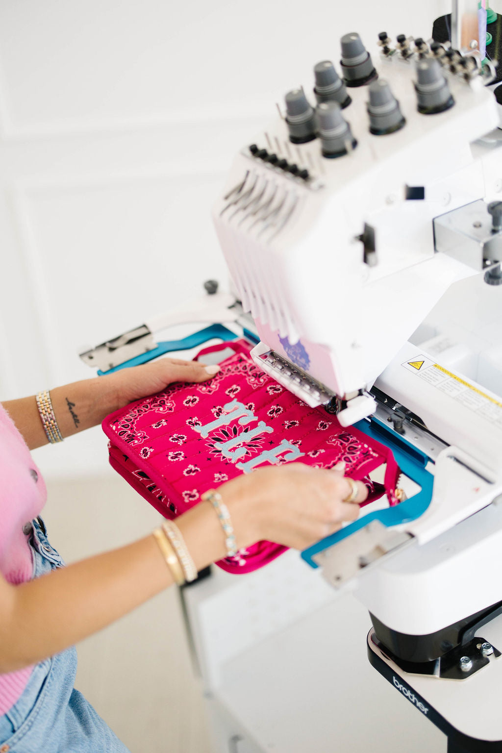 Pink bandana bag hooped on a Brother embroidery machine, TLF monogram in progress